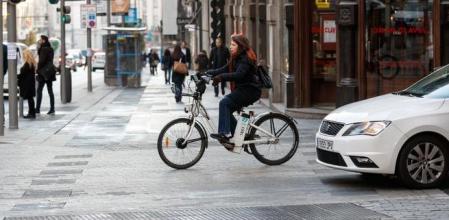 Una joven se desplaza en bicicleta eléctrica por Madrid