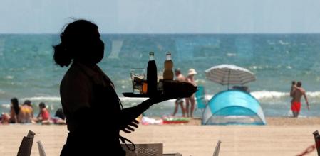 Una camarera lleva una bandeja con bebidas en un restaurante de la playa de la Malva-rosa, en València&nbsp;
