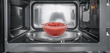 Un bol de salsa de tomate dentro del microondas