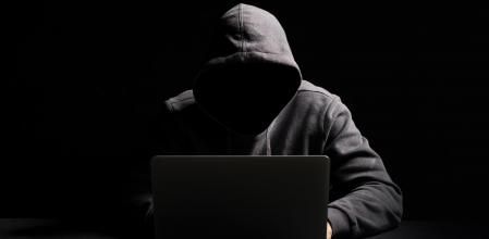 Hacker working on laptop in the dark