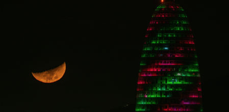 La luna creciente brilla junto a la Torre Glòries iluminada.