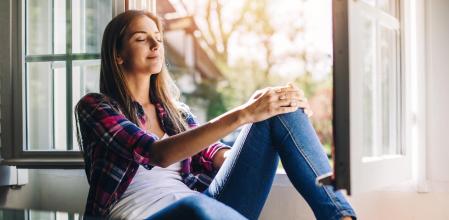 Beautiful young woman sitting at a windowsill having rest and fresh air, with copy space and country side view. Shot made during Istockalypse Paris 2016 event.