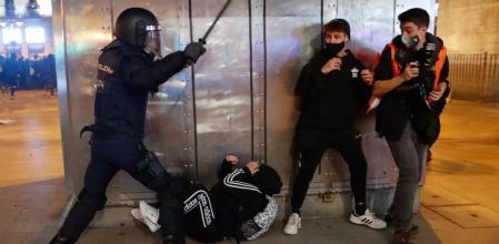 Un policía nacional con porra dispersa a manifestantes -por la detención de Hasél- y a prensa en el centro de Madrid