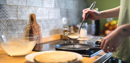 Una mujer prepara crepes en una sartén con mantequilla