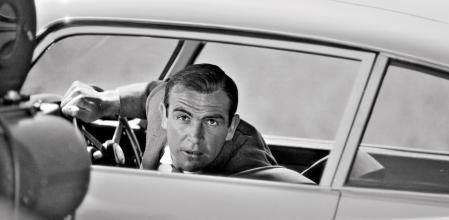 Connery, al volante del mítico Aston Martin, atiende las instrucciones del director de ‘Goldfinger’, el británico Guy Hamilton