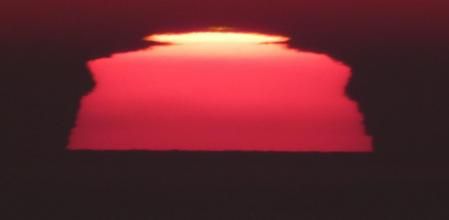 Destello o rayo verde sobre el sol al amanecer frente a la costa de Barcelona, visto desde la playa de Gavà.