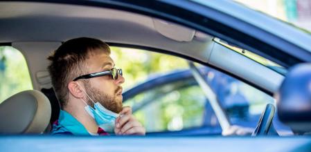 Un joven se quita la mascarilla en el coche