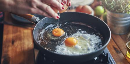 Una mujer friendo huevos en una sartén