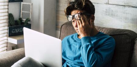 Stressed student at home studying with personal laptop computer - tired teenager for school work -internet. addiction for game or job search concept - indoor technology activity