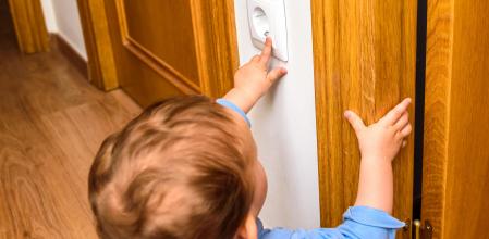 Baby introducing a finger in an electric socket, concept of childhood domestics accidents for lack of security in the home. (Baby introducing a finger in an electric socket, concept of childhood domestics accidents for lack of security in the home., A