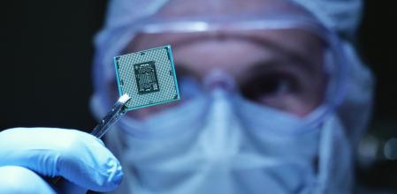 in Ultra Modern Electronic Manufacturing Factory Design Engineer in Sterile Coverall Holds Microchip with symbols in futuristic holography. artificial intelligence, future of robots.