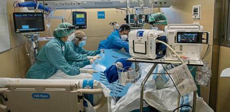 Un paciente de Covid-19 hospitalizado en un box de la UCI del hospital de la Vall d’Hebron coincidiendo con el repunte de ingresos a causa de la cuarta ola de la pandemia. Sanitarios en el ejercicio de trasladar al paciente de una camilla a una cama de la uci