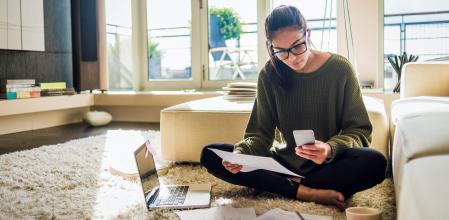 Una mujer utiliza un ordenador y un teléfono