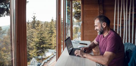 Un hombre teletrabaja desde una casa en el bosque
