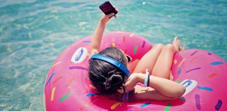 Niña en el agua mientras utiliza smartphone y auriculares