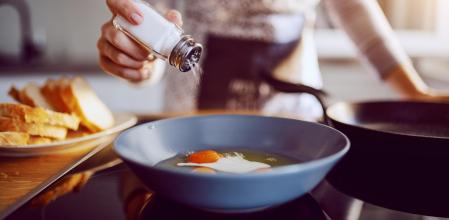 Mujer echando sal huevos