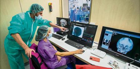 foto XAVIER CERVERA 05/08/2021 quirofano con arcoTAC ; operacion quirurgica d ampliacion del espacio craneal ; sala control bio ingenieros (Laura Palau -lila- y Xavier Escayola (responsable) -verde- mirando pantallas) q participan in-situ y en directo durante operaciones quirurjicas ,en hospital sant joan de deu ,esplugues de llobregat (barcelona) centre de control d imatge i neurofisiologia