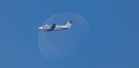 Avioneta sobrevolando junto a la luna.