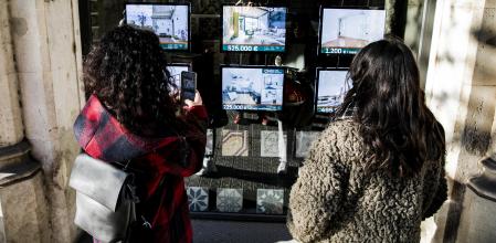 Dos jóvenes consultan pisos en una inmobiliaria