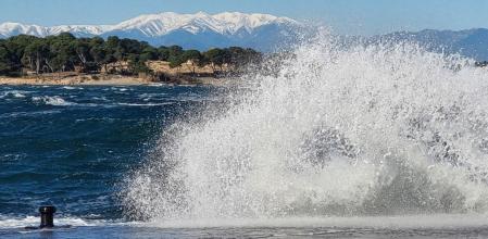 Golpe de mar con tramontana en L'Escala, con el Canigó al fondo.