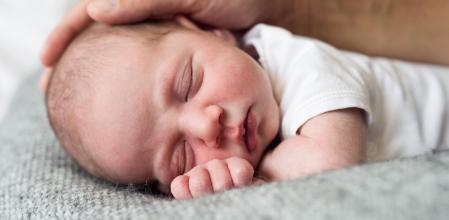 Un padre acaricia a su bebé recién nacido