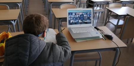 El único alumno en el aula se comunica con sus compañeros por videoconferencia.