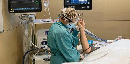 Un paciente de Covid-19 hospitalizado en un box de la UCI del hospital de la Vall d’Hebron coincidiendo con el repunte de ingresos a causa de la cuarta ola de la pandemia. Una sanitaria estabilizando al paciente tras haber sido trasladado