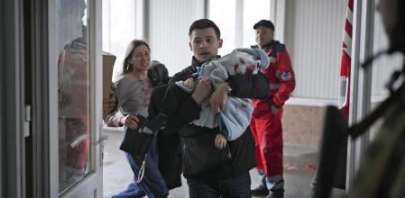 Marina Yatsko, left, runs behind her boyfriend Fedor carrying her 18 month-old son Kirill who was killed in shelling, as they arrive at a hospital in Mariupol, Ukraine, Friday, March 4, 2022. (AP Photo/Evgeniy Maloletka)