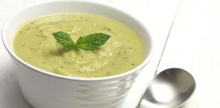 Bowl of fresh soup with spoon on table top