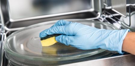 Una persona limpia el microondas