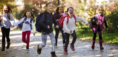 Un grupo de niños corriendo de camino al colegio