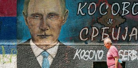 A man passes by graffiti depicting Russian President Vladimir Putin, reading: 