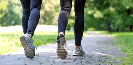 Wellness and fitness concept - low angle view of running women in the park on a sunny morning.