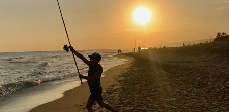 Un pescador tirando la caña en la playa de Gavà.