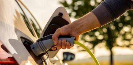 Una persona conecta el cargador a su vehículo eléctrico