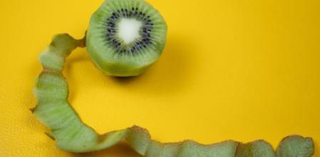 Top view of peeled kiwi on white background. Peel is looking like a snake