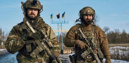 Ukrainian soldiers walk against the background of a sign reading 