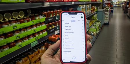 Un consumidor consulta la lista de la compra confeccionada en un smparthone mientras visita un supermercado