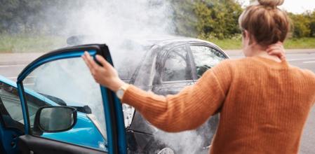 Una joven se toca las cervicales después de haber sufrido un accidente de tráfico con su coche
