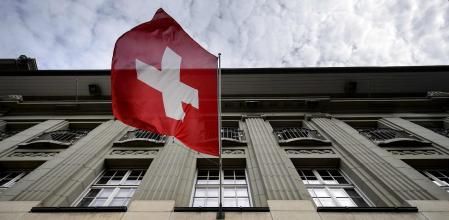 Una bandera suiza ondea sobre un letrero del banco suizo Credit Suisse en Berna, Suiza.