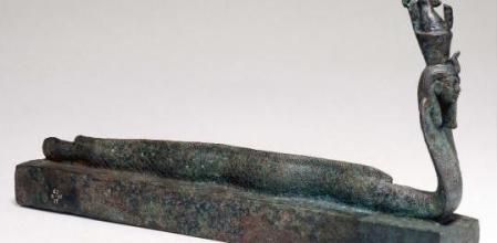 Ataúd de animal coronado por una criatura mitad anguila mitad cobra con cabeza humana que lleva una corona doble, asociada con el antiguo dios egipcio Atum