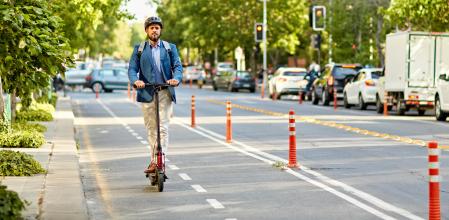 Full length view of mid adult man in professional attire and helmet commuting to work in downtown district.