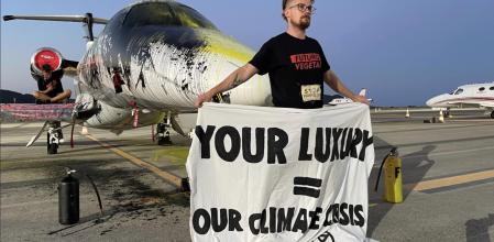 Un activista climático sujeta una pancarta de protesta tras rociar con pintura el jet privado&nbsp;