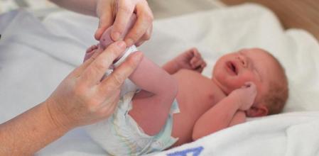 a Paediatrician administers a heel prick test to check sucrose levels in a newborn baby boy after a caesarean section.