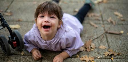 The girl is tired. She doesn't want to walk and she doesn't want to ride in a stroller, so she decided to lie down and cry.