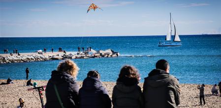 foto XAVIER CERVERA 07/01/2024 escollera espigon d la playa la mar bella, barcelona, al fondo izquierda, y mas en primer termino, ciudadanos o turistas en la playa d bogatell observan un velero, cometa, windsurfistas,.. (en el mar, por esta zona, se ubicara l inauguracion de la copa america)