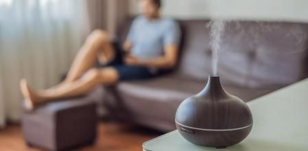 Una persona en el comedor de su casa usando un humidificador de aceites esenciales.