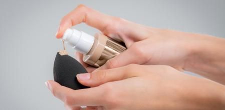 Una mano poniendo base de maquillaje sobre una beauty blender.