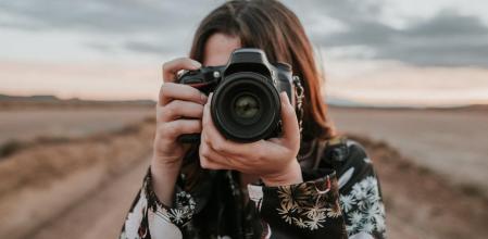 Una mujer usando una cámara réflex.