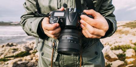 Un hombre ajustando la cámara réflex para hacer una foto.